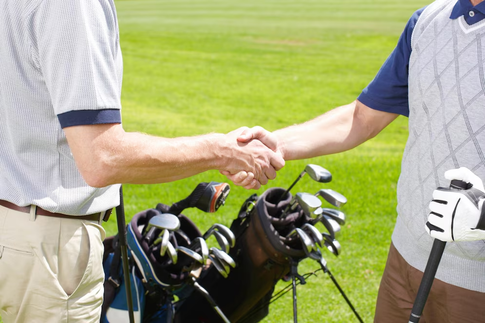 Two golfers shaking hands on a golf course