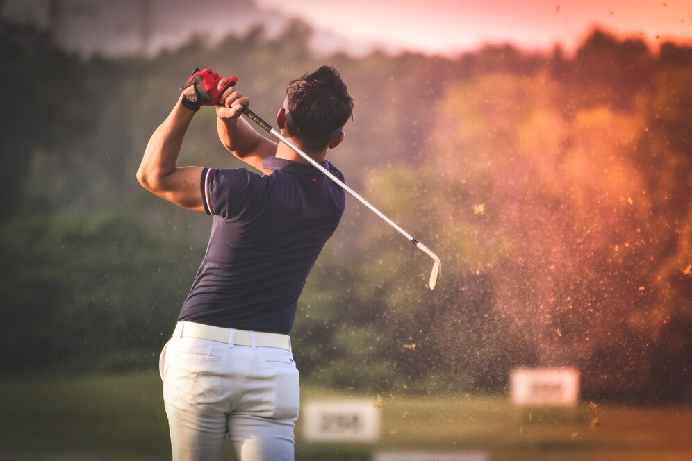 Golfer taking a shot at sunset.